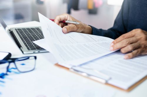 Person mit Dokumenten und Laptop